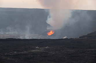 Lava erupting from vent in side of Halemaumau Crater with smoke (vog) rising.